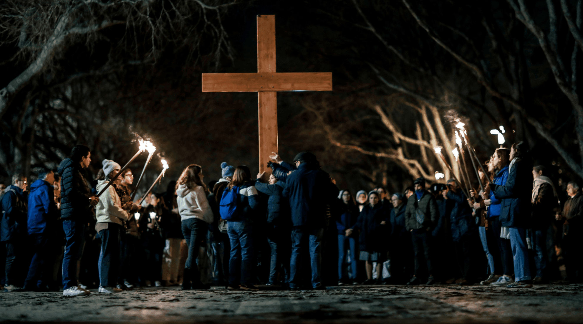 Jovens elevam répicas da Cruz da JMJ ao centro, rodeados de jovens que seguram tochas
