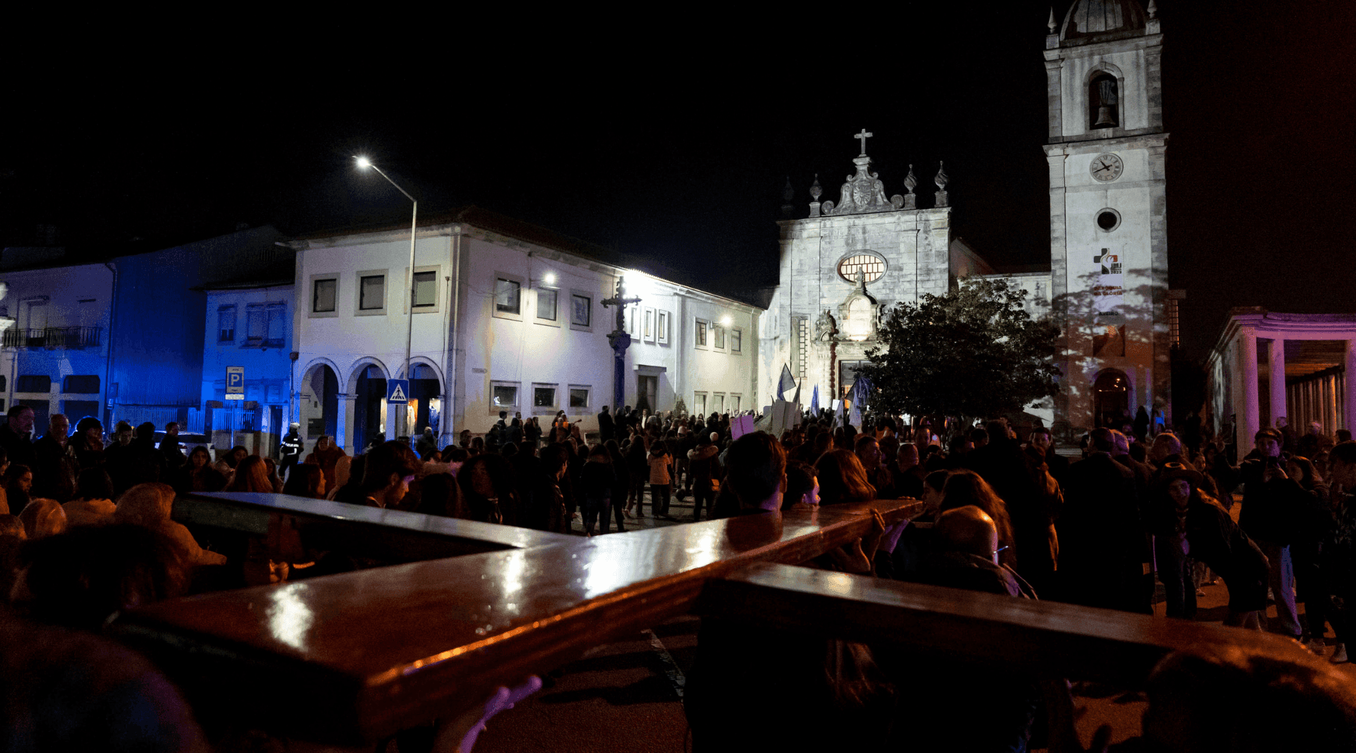 Símbolos da JMJ a chegar à Sé de Aveiro, com uma multidão à espera. Foto tirada à noite, com a Sé iluminada ao fundo