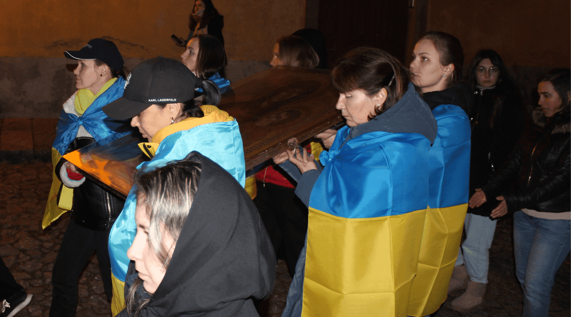 Mulheres com bandeiras da Ucrânia às costas carregam a Cruz da JMJ