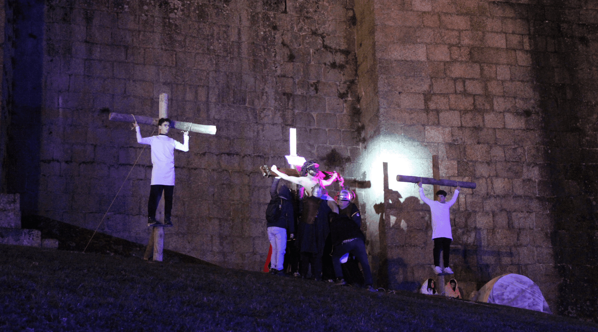 Três jovens encenam a crucificação de Jesus, junto ao Castelo de Guimarães