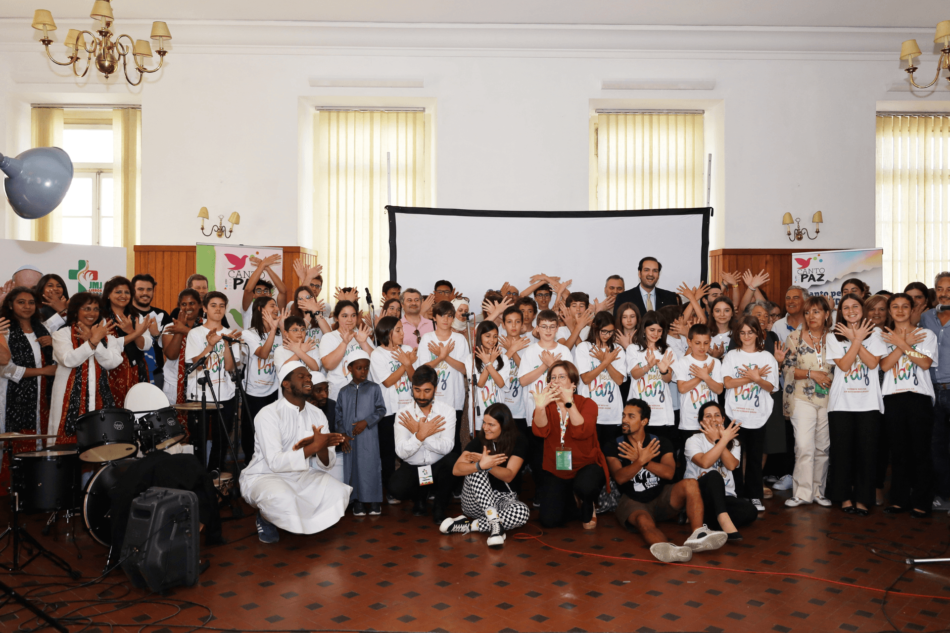 Pessoas de diferentes culturas e religiões a fazerem o símbolo da pomba da Paz com as mãos