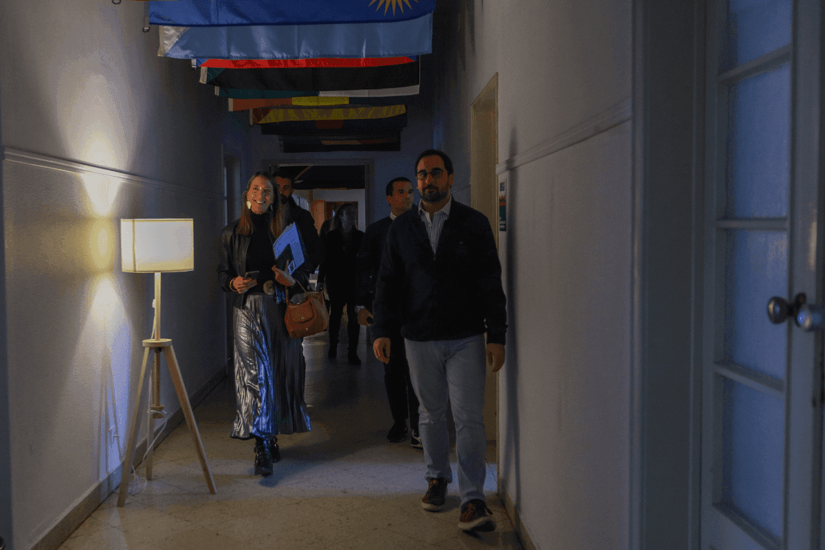 Representantes das Juntas de Freguesia de Lisboa em visita à sede do COL, num corredor. Foto escurecida, com um candeeiro de pés a ser o foco de luz da foto