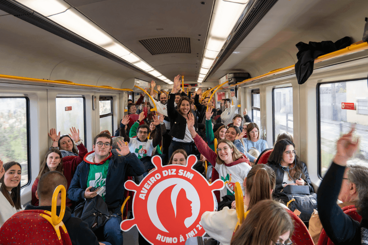 Jovens de Aveiro no comboio, de braços levantados e de sorriso na cara