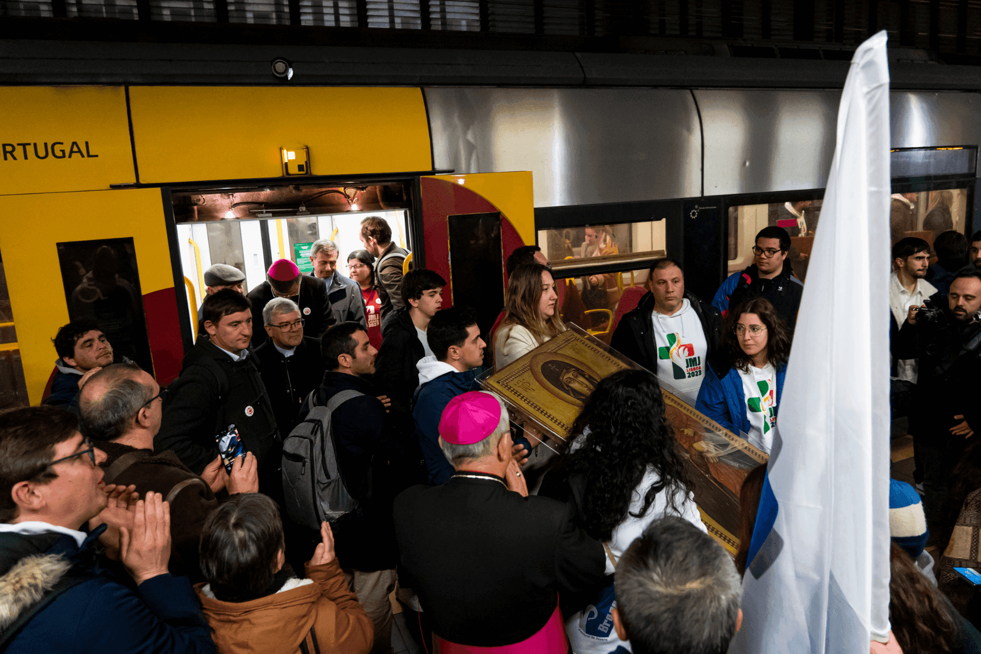Jovens carregam os Símbolos da JMJ ao saírem do comboio, rodeados de uma multidão