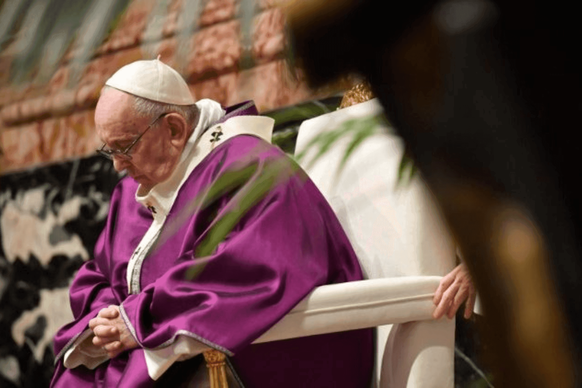 Papa Francisco com paramento roxo, a olhar para baixo num momento de reflexão